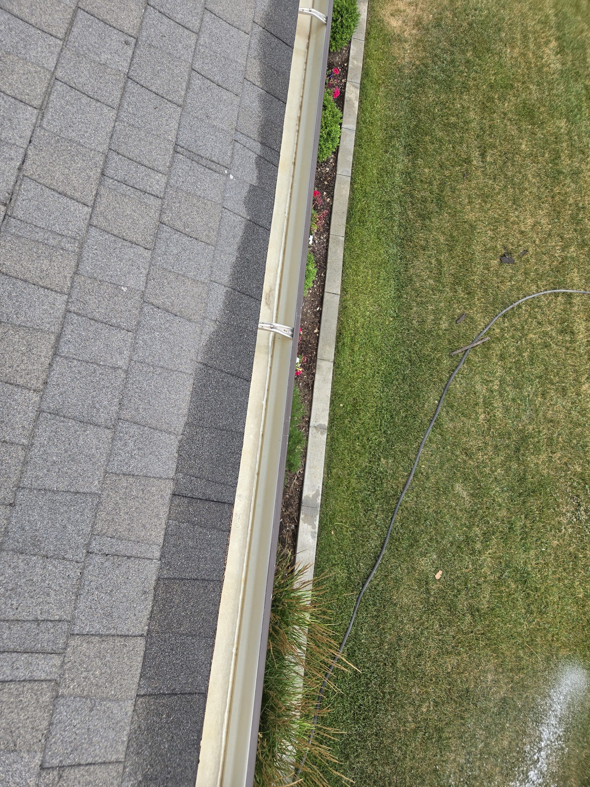 Cleared gutter along the roofline above the lawn