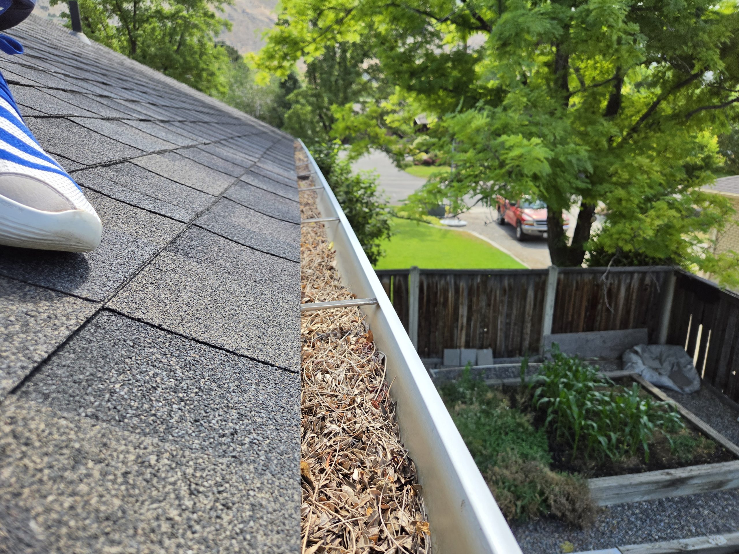 View down a cleared gutter along the roofline with a wood fence below